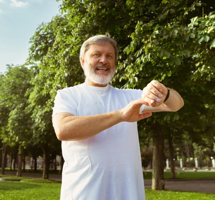An older man outdoors checking his watch, suggesting an unhurried daily routine